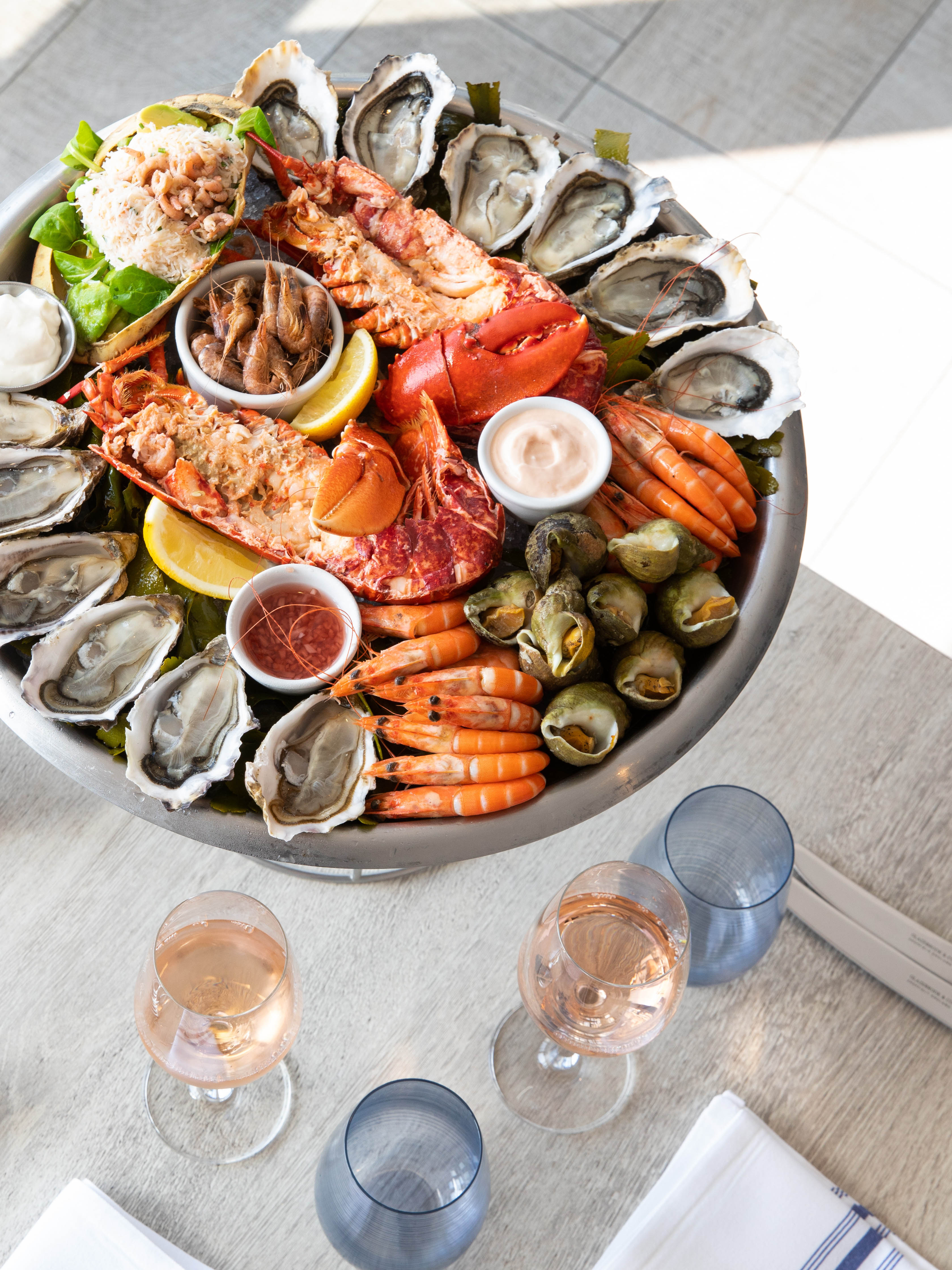A large seafood platter shown proudly on a table, with crevettes, lobster, oysters, whelks, and trimmings.