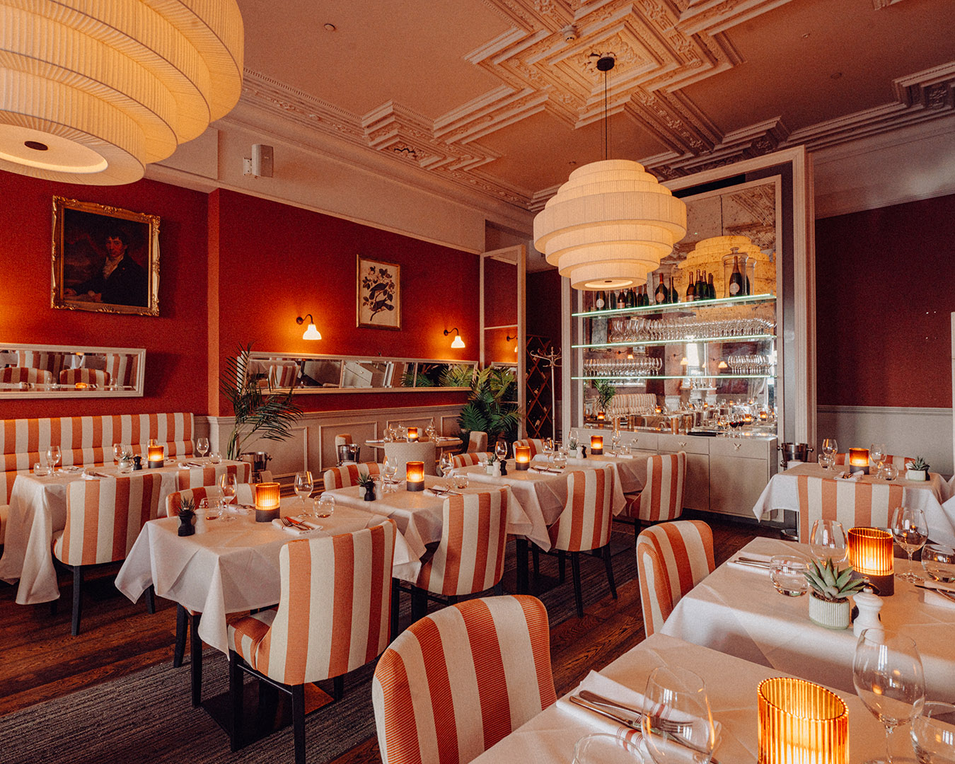 The Beresford House dining room, decorated in warm colours with large glowing lampshades and orange colour accents