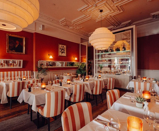 The Beresford House dining room, decorated in warm colours with large glowing lampshades and orange colour accents