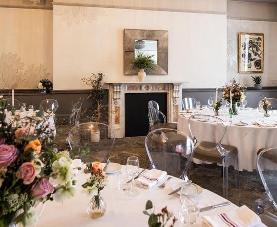 A large dining table with a white linen cloth in an elegant Victorian-style private room