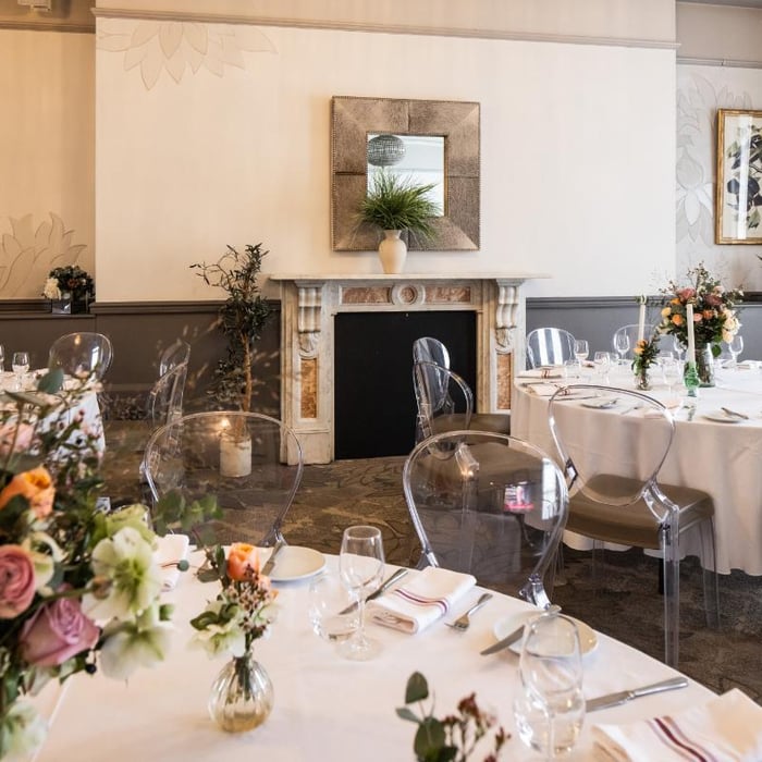 A large dining table with a white linen cloth in an elegant Victorian-style private room