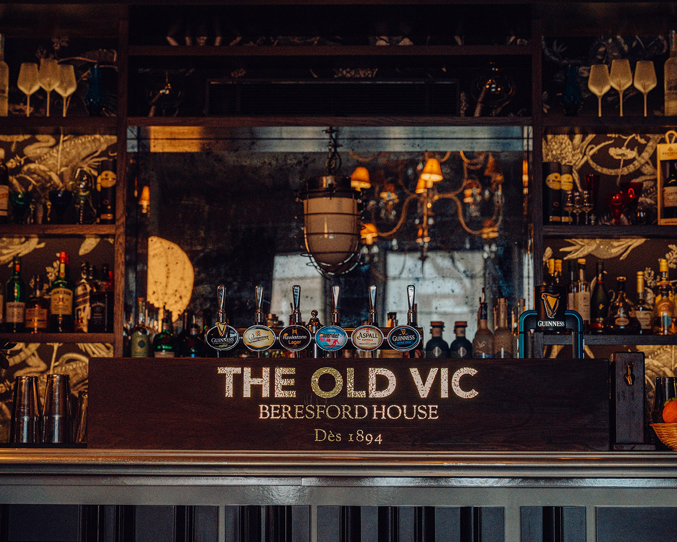 A bar with THE OLD VIC logo displayed, warm lighting, and a range of beer taps