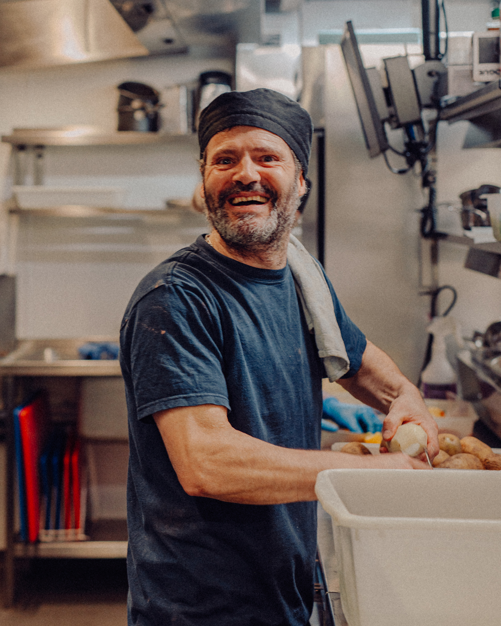 A Back of House team member smiles while preparing potatoes
