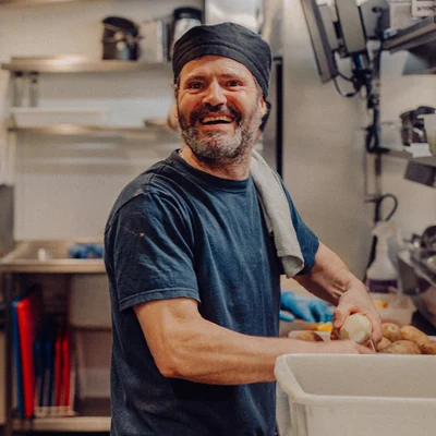 A Back of House team member smiles while preparing potatoes