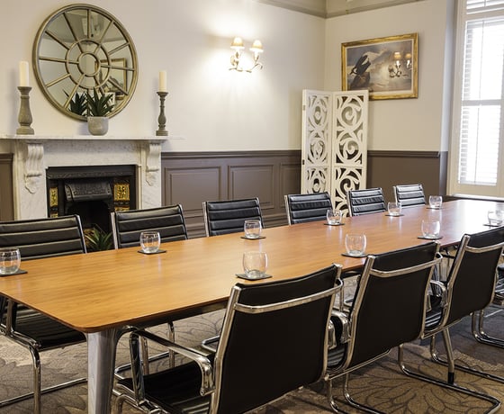 A boardroom with a large wooden board table and leather seats