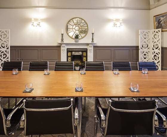 A boardroom with a large wooden board table and leather seats