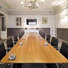 A boardroom with a large wooden board table and leather seats