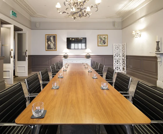 A boardroom with a large wooden board table and leather seats