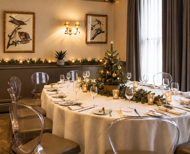 A dining room decorated for Christmas, with lights and festive decorations