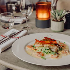 A fish dish, simply plated, on a stylish marble table