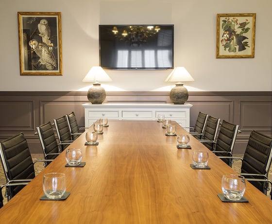 A boardroom with a large wooden board table and leather seats