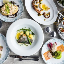 A table filled with seafood dishes, including oysters, octopus, trout, bass, and crab