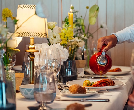 A waiter pours sauce over a main course on a beautifully decorated table