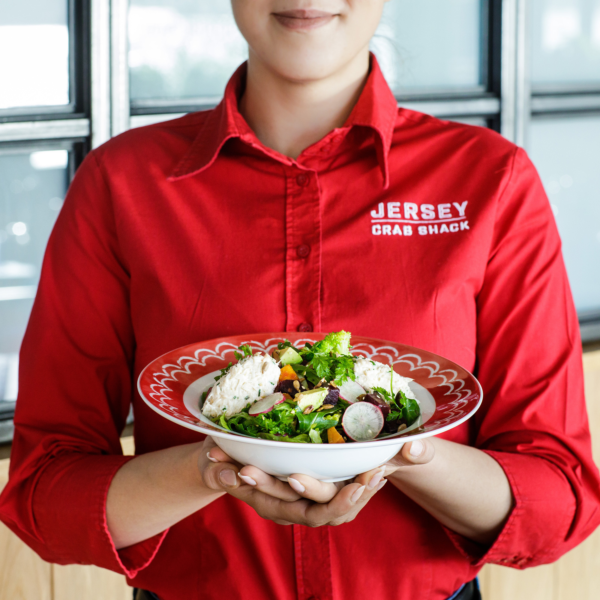 A team member holds a bowl of crab salad