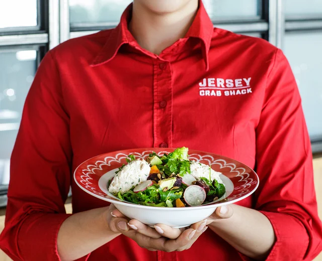 A team member holds a bowl of crab salad