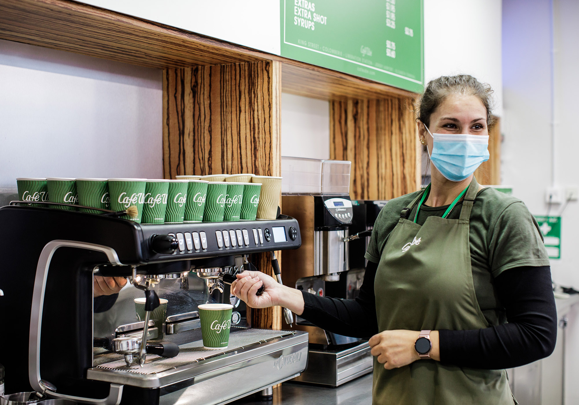 A server in a face mask prepares coffee during the COVID 19 pandemic