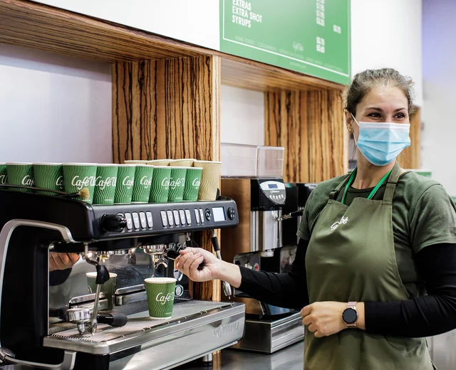 A server in a face mask prepares coffee during the COVID 19 pandemic