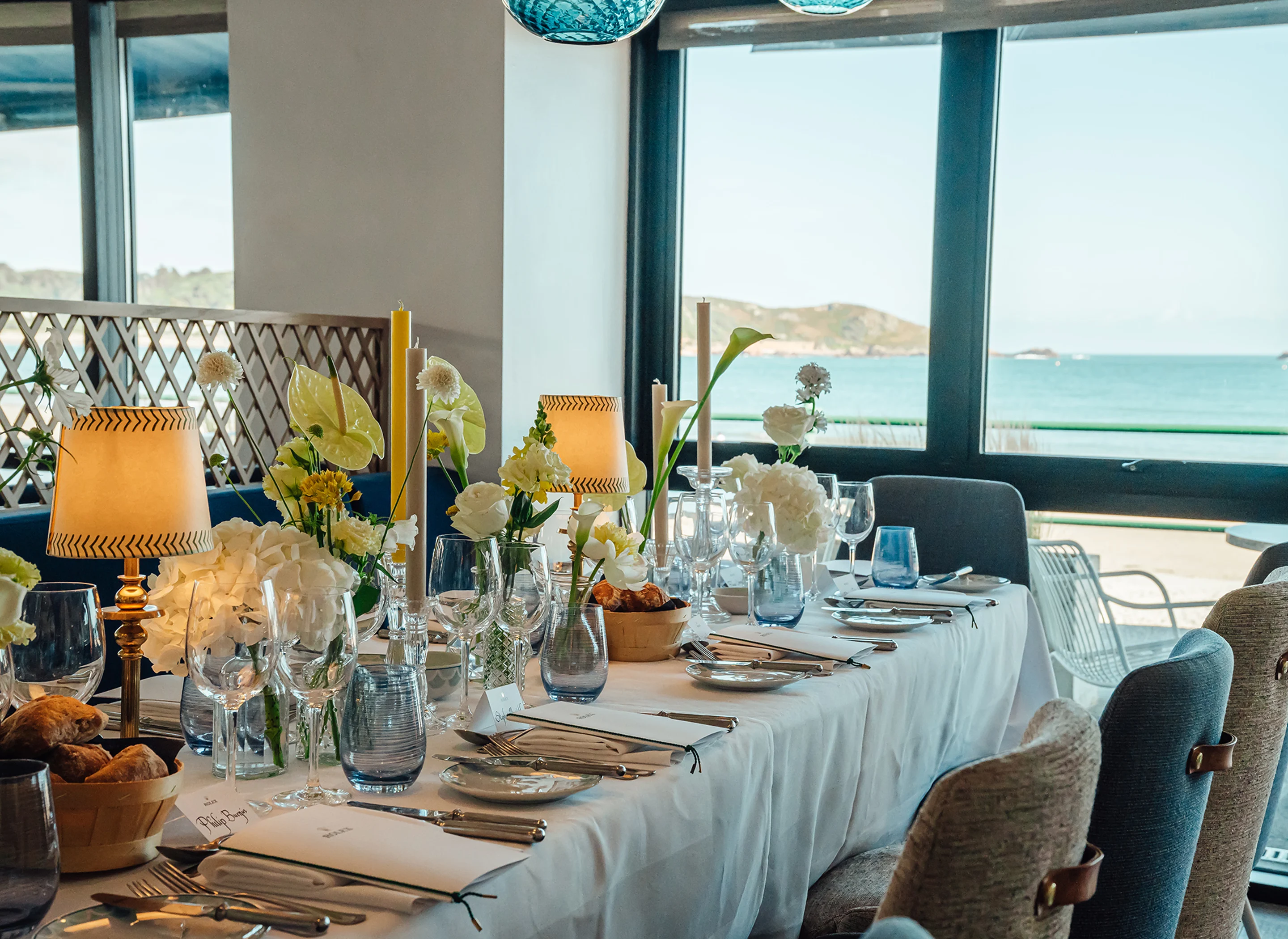 A dining table set up for a private event with floral decorations and views over the Bay