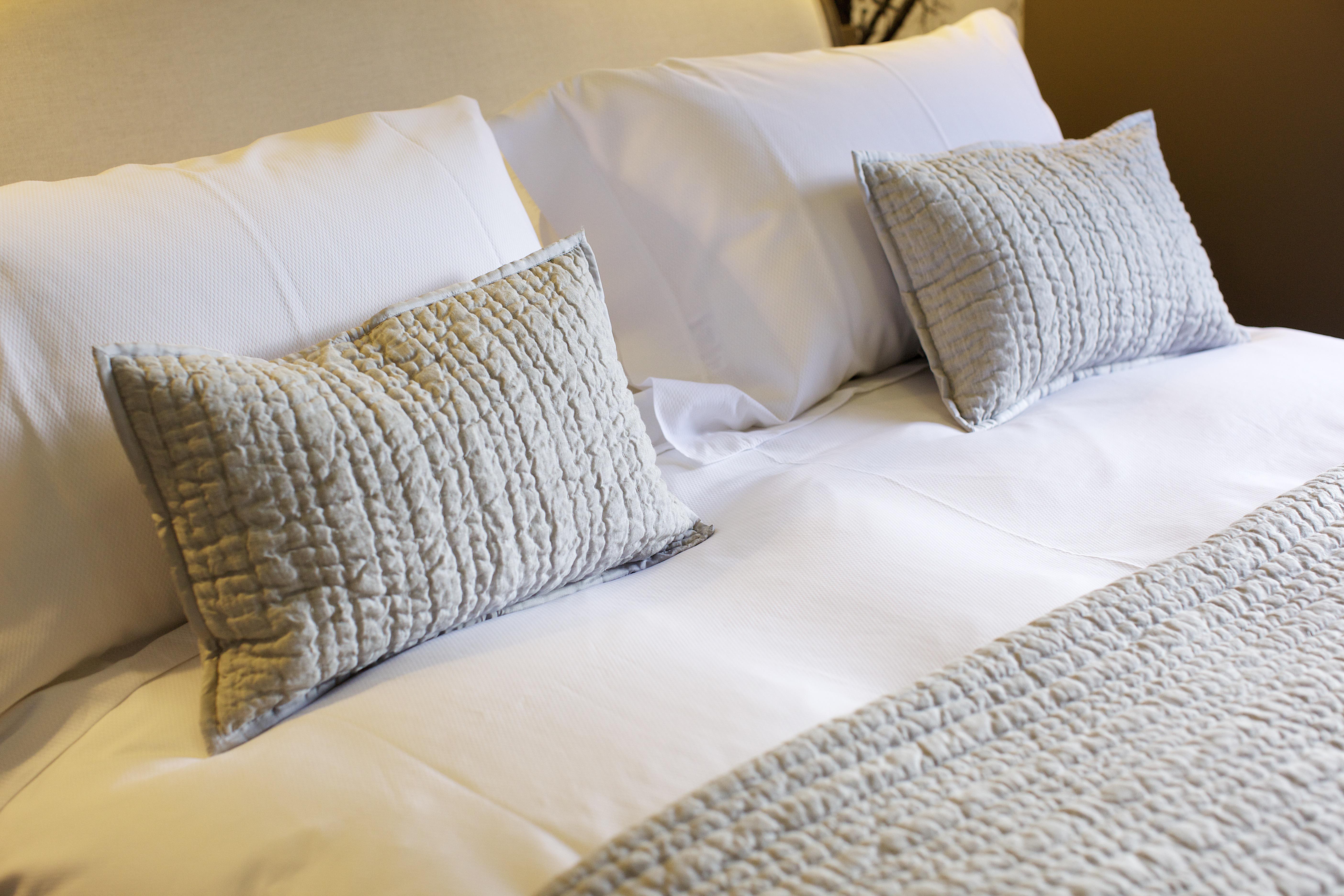 A cosy hotel bed with Egypitan cotton linens and decorative scatter cushions