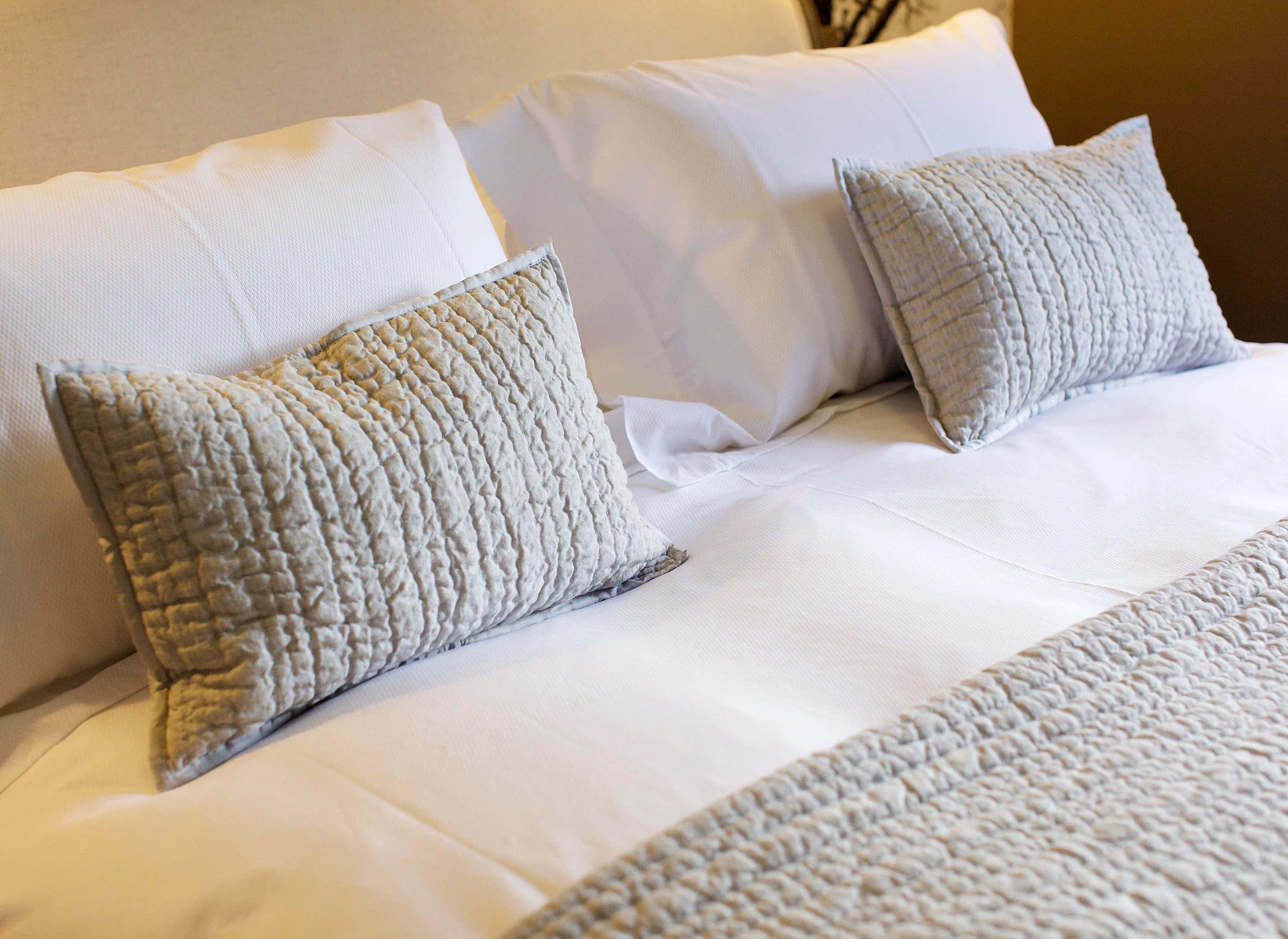 A cosy hotel bed with Egypitan cotton linens and decorative scatter cushions
