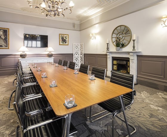 A boardroom with a large wooden board table and leather seats