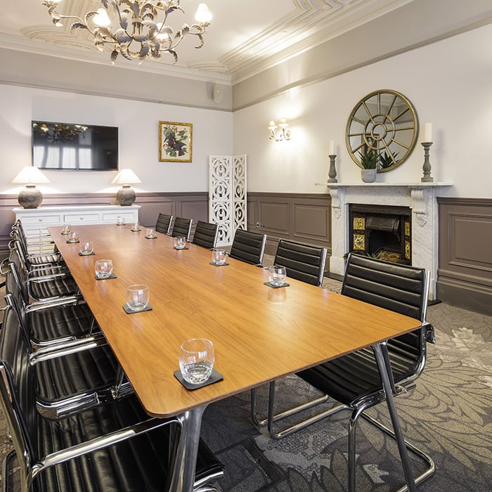 A boardroom with a large wooden board table and leather seats