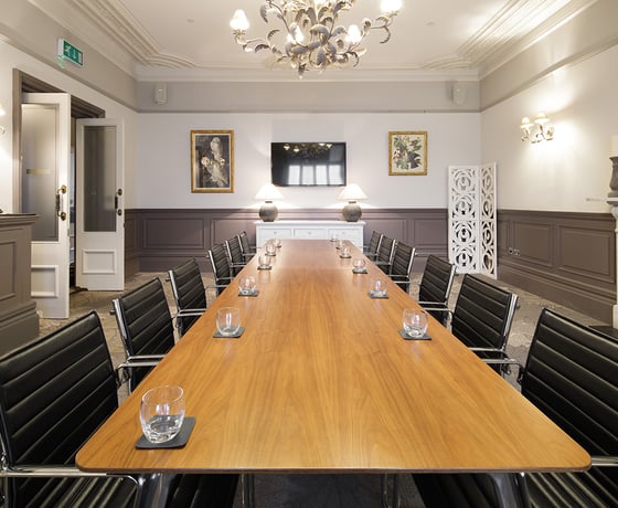 A boardroom with a large wooden board table and leather seats