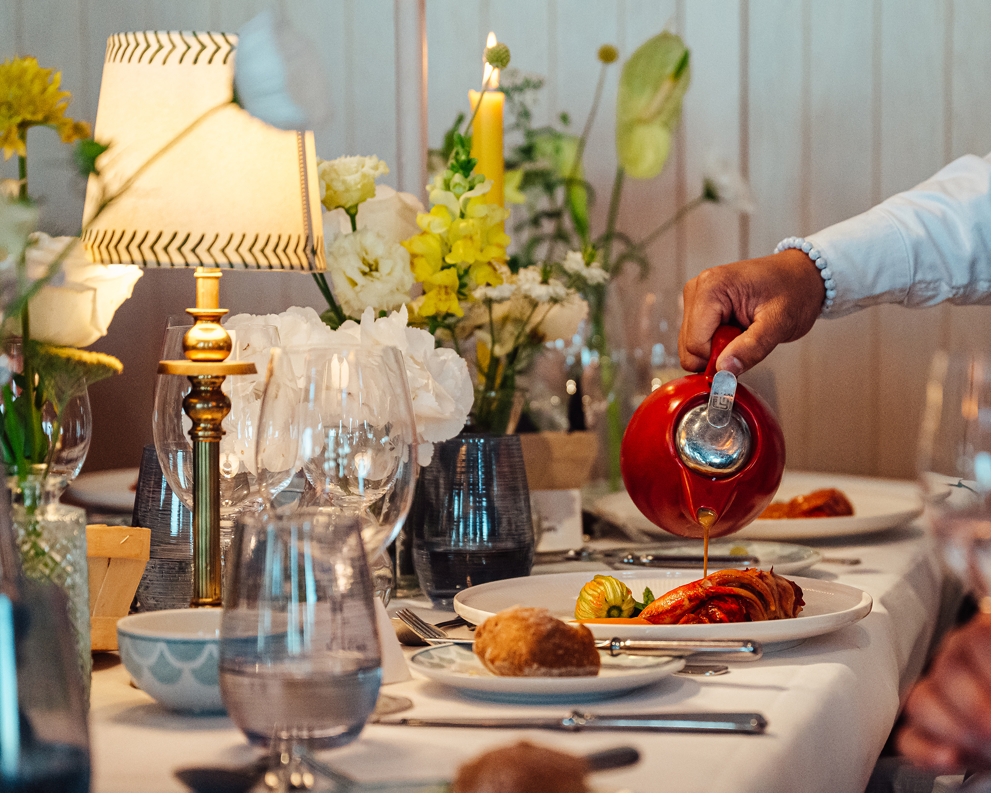 A server pours sauce over a main course at an event
