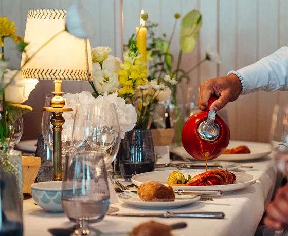 A server pours sauce over a main course at an event