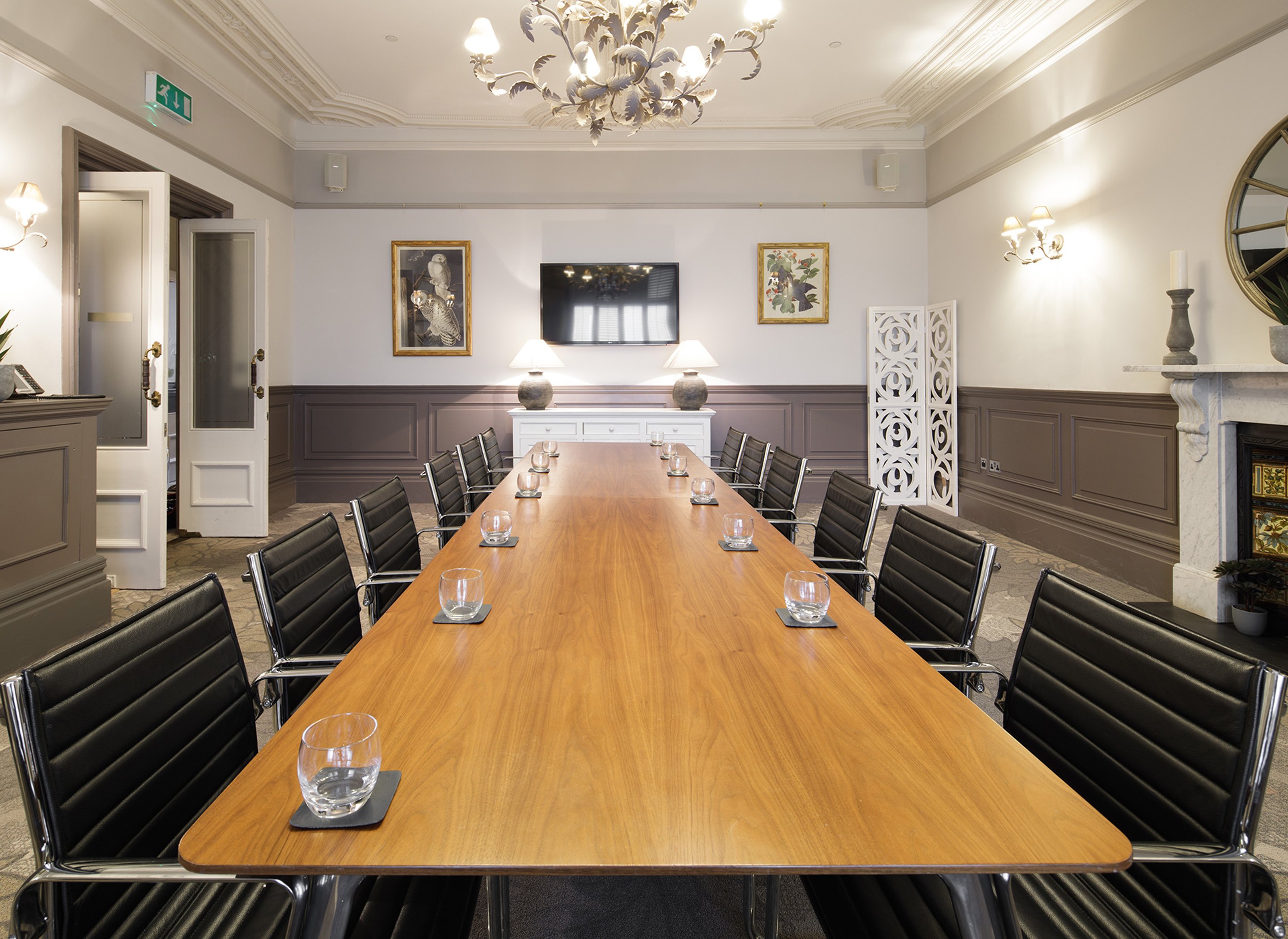 A boardroom with a large wooden board table and leather seats