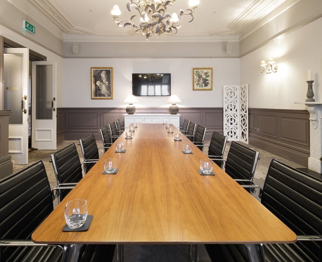 A boardroom with a large wooden board table and leather seats