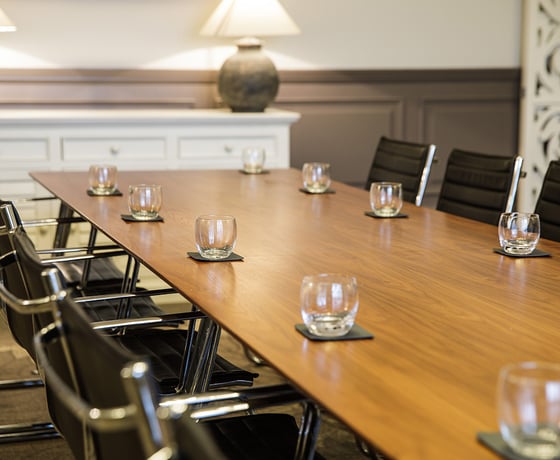 A boardroom with a large wooden board table and leather seats