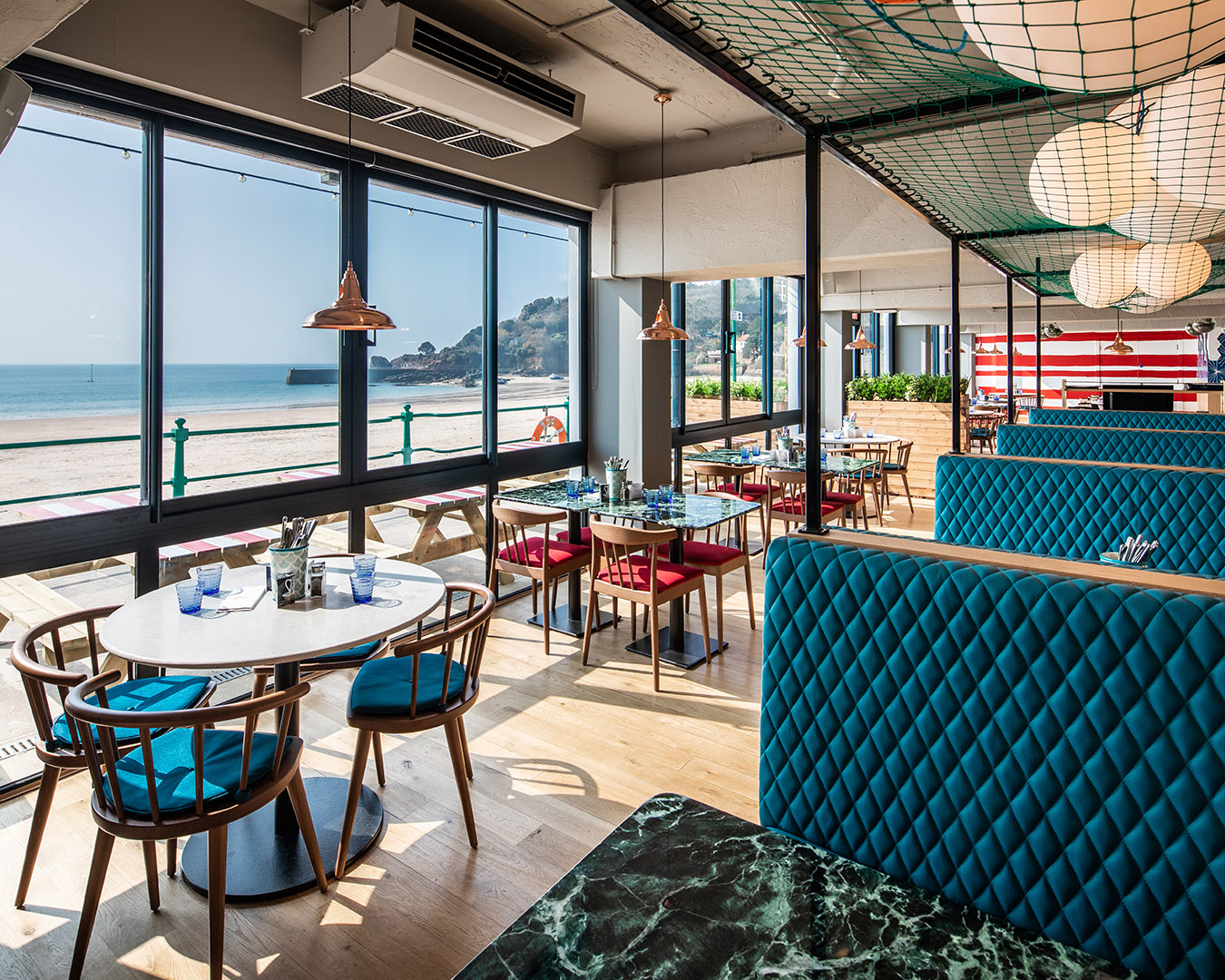The interior of a nautically-themed seaside restaurant with views over the sand and ocean