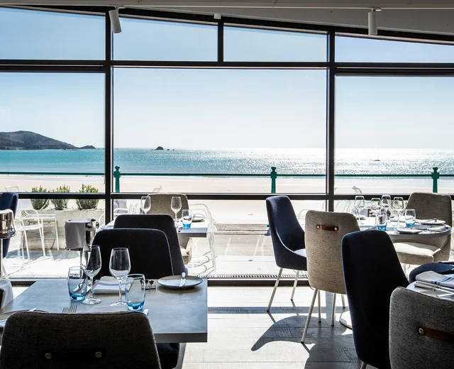 An elegant seaside restaurant interior, including sweeping views over the beach