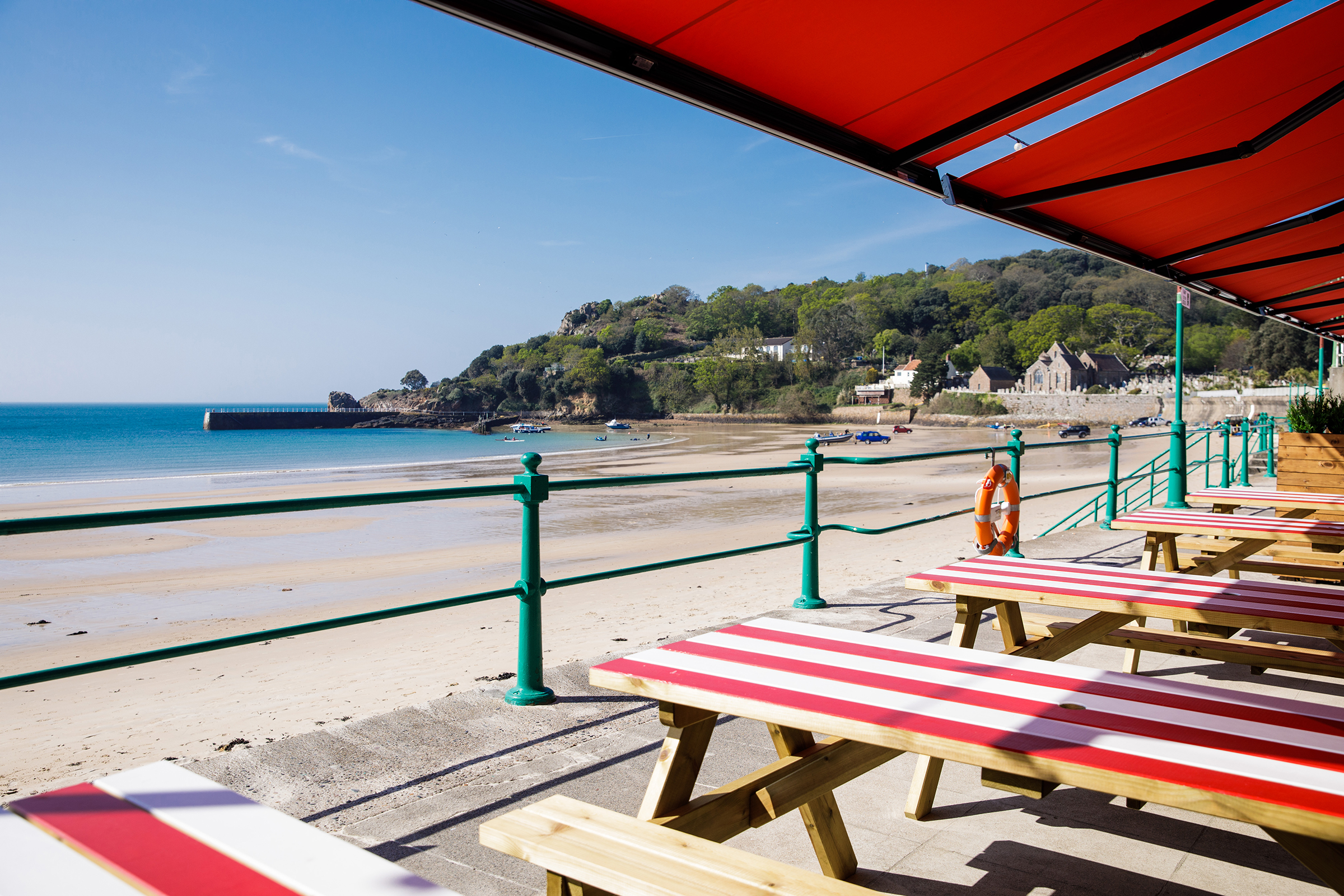 A view of St Brelade's Bay with Jersey Crab Shack's red and white tables in the foreground