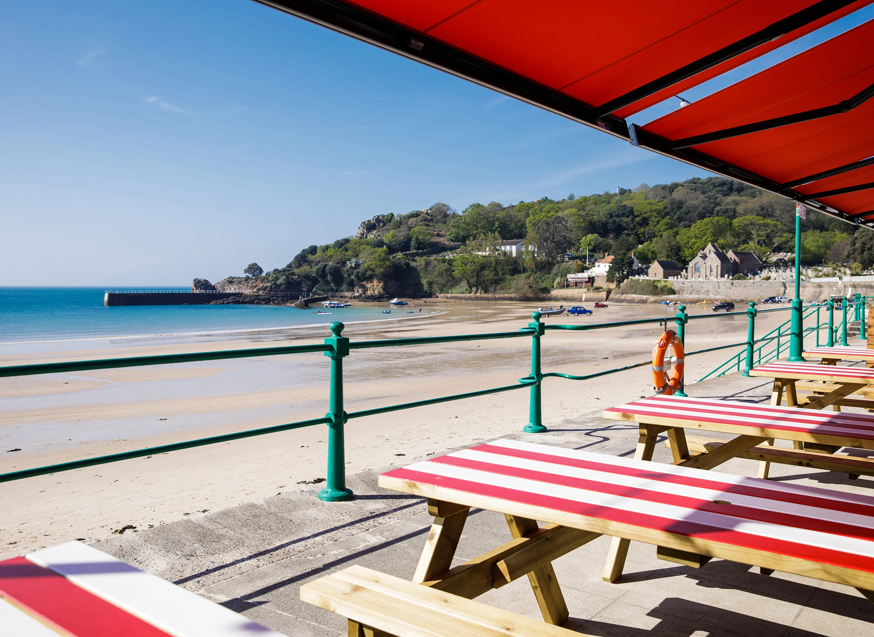 A view of St Brelade's Bay with Jersey Crab Shack's red and white tables in the foreground