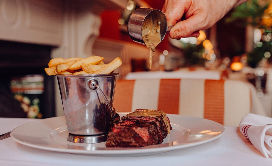 A server pours sauce over a steak