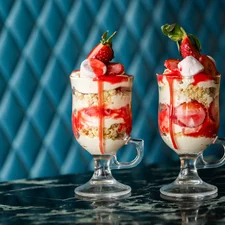 Two tall strawberry trifles in elegant sundae-style glasses