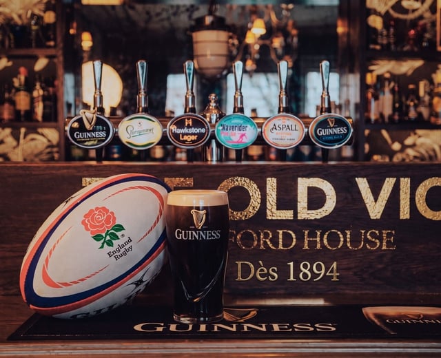 A rugby ball leans against a pint of Guinness at The Old Vic bar
