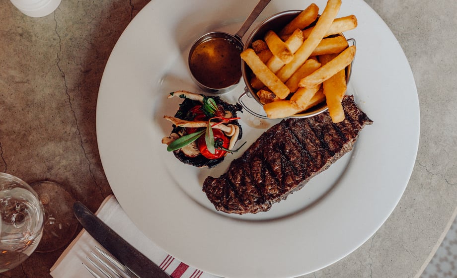 A grilled steak served with chips and vegetables