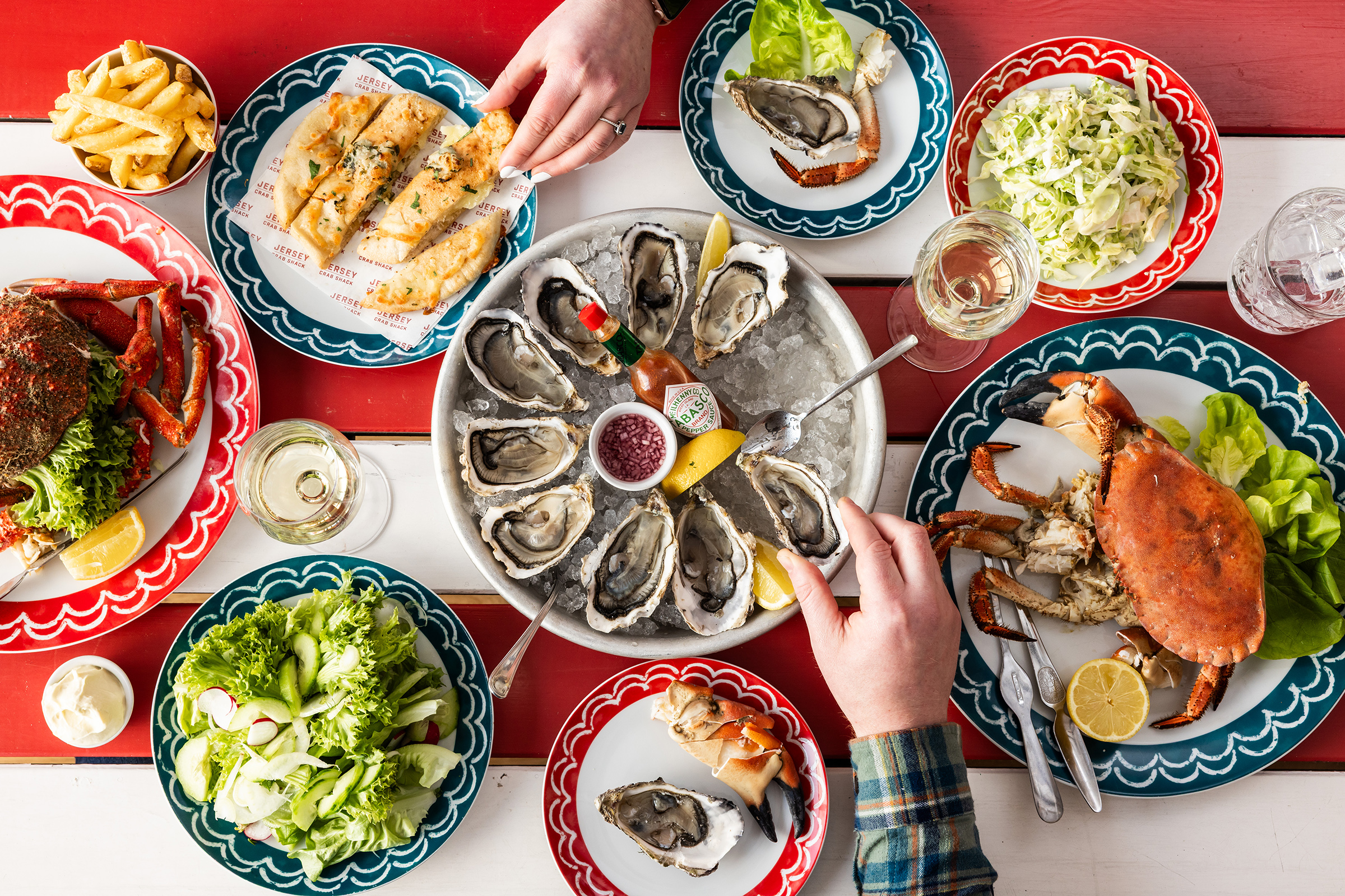A red and white striped table filled with seafood dishes, including oyster and crab