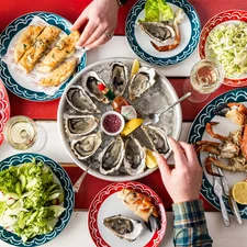 A red and white striped table filled with seafood dishes, including oyster and crab