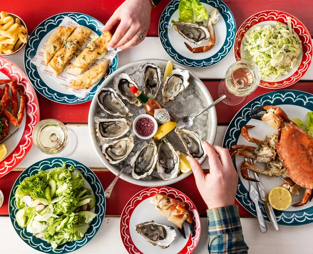A red and white striped table filled with seafood dishes, including oyster and crab
