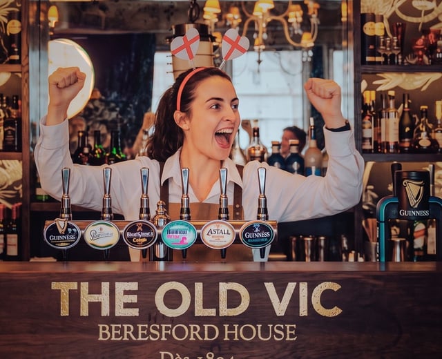 A team member cheers for England, while serving behind the bar at The Old Vic