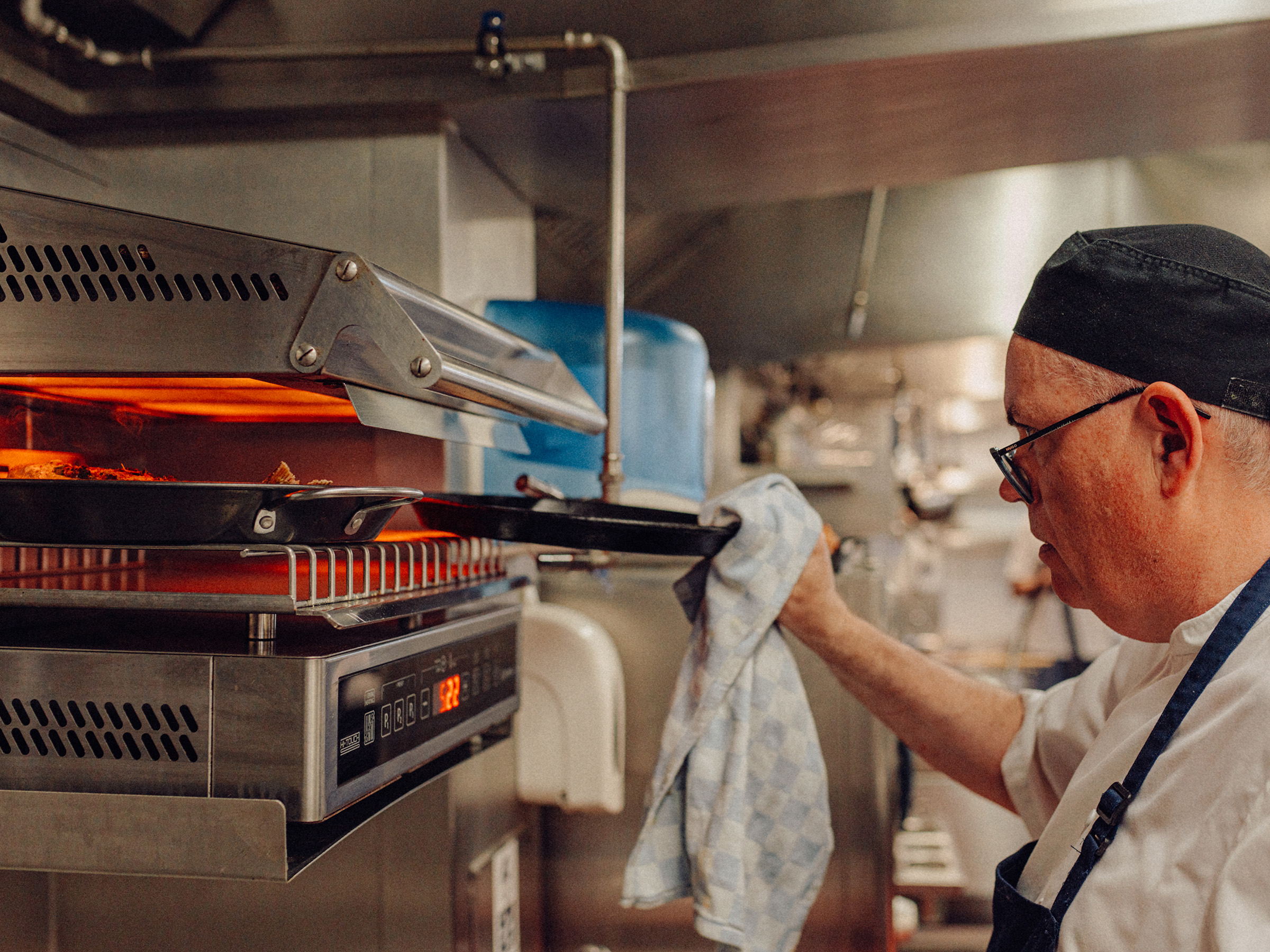 A chef grills food in a commercial kitchen