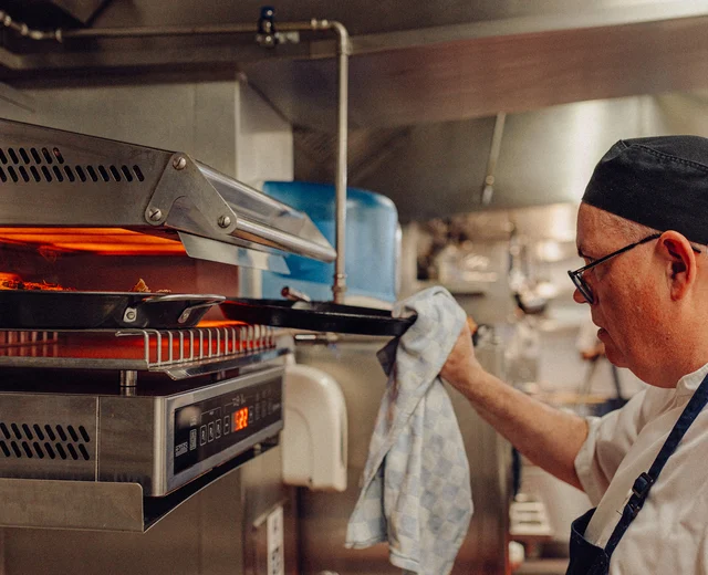 A chef grills food in a commercial kitchen