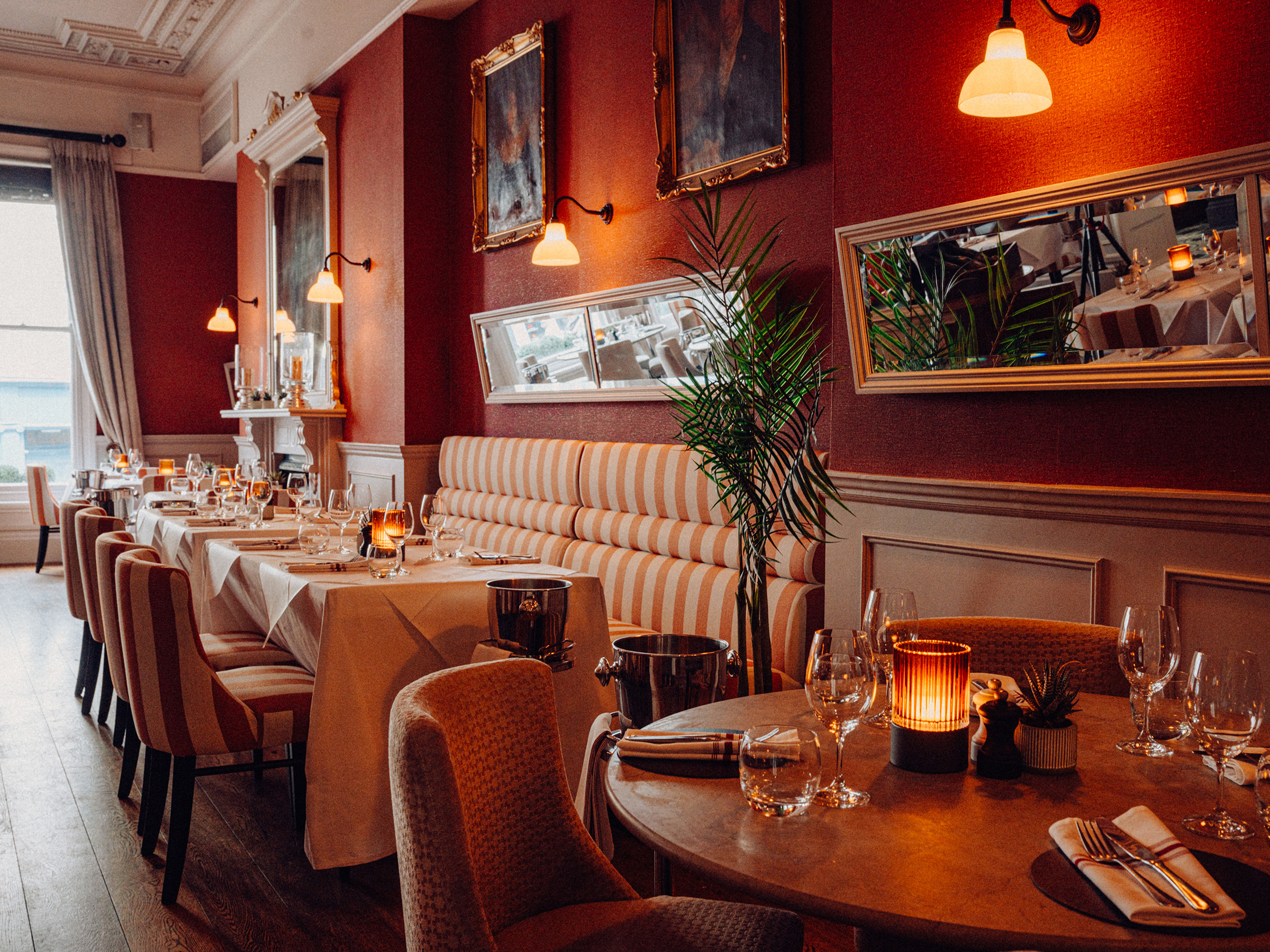 The elegant Cote d'Azur-inspired Dining Room at Beresford House, with cream and coral upholstery, rich orange walls, and textured fabrics
